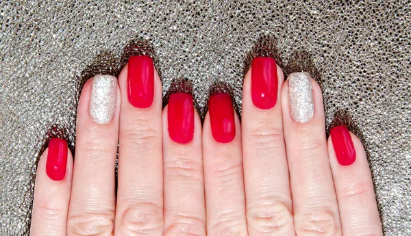 Woman's nails with beautiful red manicure fashion design with gems