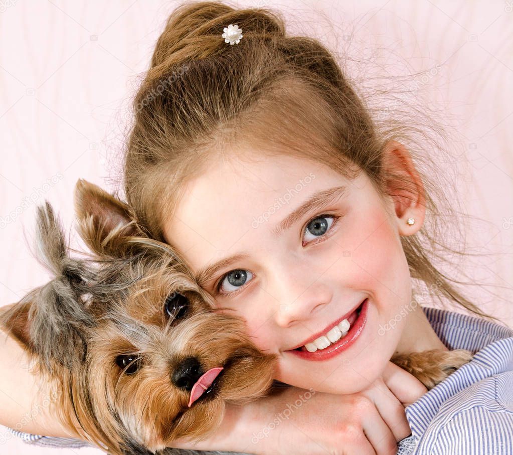 Adorable smiling little girl child holding and playing with pupp