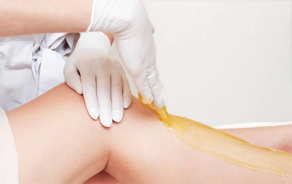 Kosmetolog kosmetyczka woskowanie kobiece nogi w centrum spa być — Zdjęcie stockowe