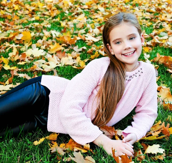 Podzimní portrét roztomilého usmívajícího se dítěte ležícího na — Stock fotografie