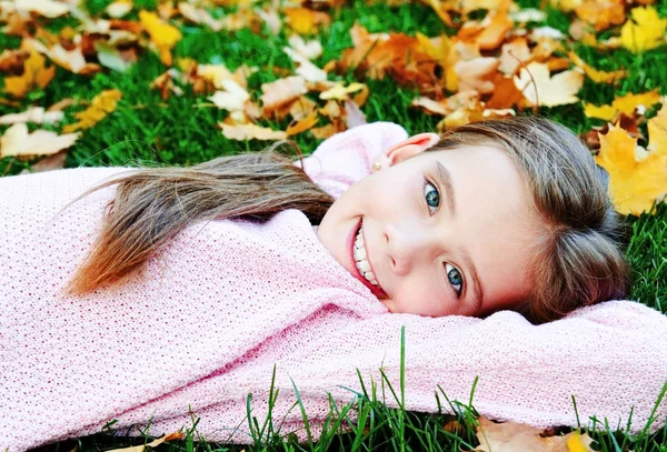 Podzimní portrét roztomilého usmívajícího se dítěte ležícího v — Stock fotografie