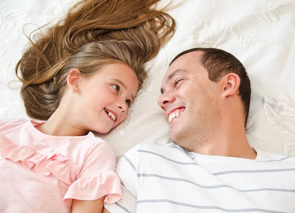 Улыбающийся счастливый отец со своей маленькой дочерью, лежащей на — стоковое фото