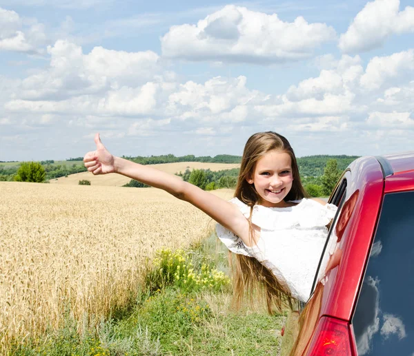 Счастливая маленькая девочка девочка с пальцем вверх идет на летнюю траву — стоковое фото