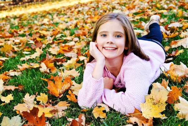 Herbst-Porträt des bezaubernd lächelnden kleinen Mädchens Kind auf liegen — Stockfoto