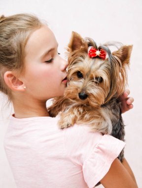 Sevimli gülümseyen mutlu küçük kız çocuk köpek yavrusu York ile oynuyor