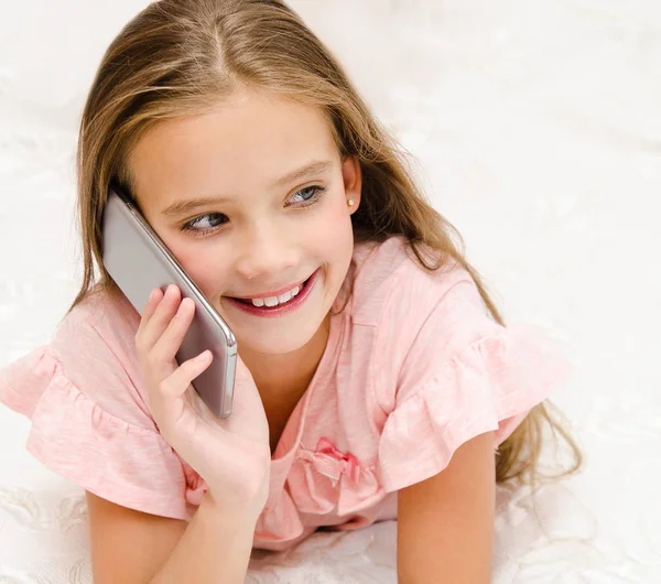 Портрет милой улыбающейся маленькой девочки, звонящей по сотовому телефону — стоковое фото