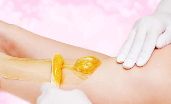 Cosmetologist beautician waxing female legs in the spa center be — Stock Photo, Image