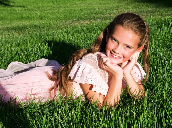 Bedårande lycklig liten flicka barn som ligger på gräset i parken — Stockfoto