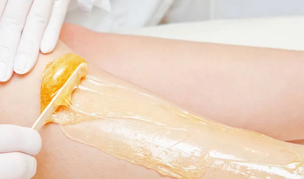 Kosmetolog kosmetyczka woskowanie kobiece nogi w centrum spa być — Zdjęcie stockowe