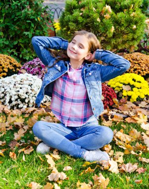 Dışarıda oturan sevimli, gülümseyen küçük bir kızın portresi. 