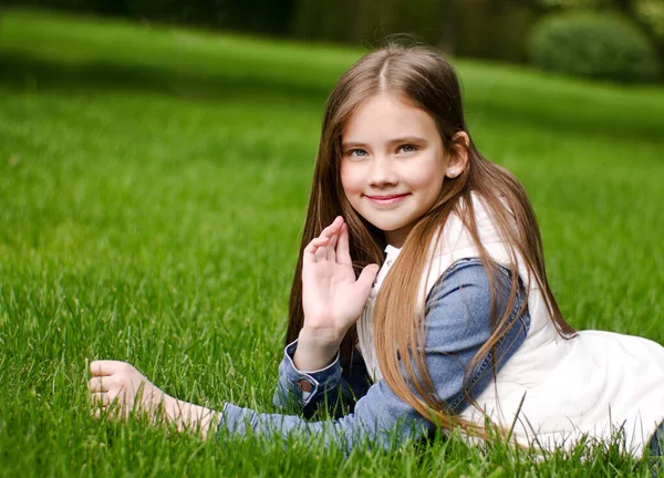 在公园外的草地上躺着可爱的微笑的小女孩的画像 — 图库照片