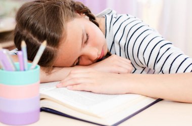 Okula dönelim. Ödev yaparken masada uyuyan yorgun küçük kız çocuğu. Eğitim öğrenme kavramı 