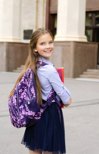 Back to school. Education concept. Cute smiling schoolgirl on the way to the school. Happy little girl child holding the books with backpack