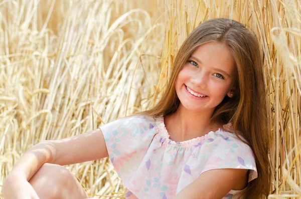 笑顔かわいい女の子の子供の肖像画は 小麦の屋外のフィールドに座って — ストック写真