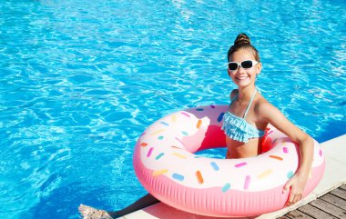 Plastik yüzükle havuzda yüzen tatlı küçük kız. Çocuk yaz tatilinde eğleniyor