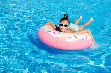 Plastik yüzükle havuzda yüzen tatlı küçük kız. Çocuk yaz tatilinde eğleniyor