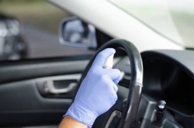 Adam arabasının tekerleğini ve salonunu dezenfekte ediyor. Koruyucu eldivenli bir erkek dezenfektan tutuyor. Dezenfeksiyon hijyeni ve koronavirüs konsepti 