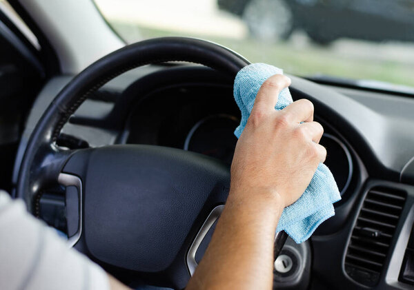 Cleansing car interior and wheel. Male hand  disinfecting vihicle inside for protection from virus disease