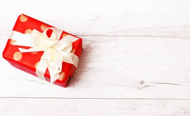 Mutlu Noeller ve mutlu yıllar. Noel hediyesi olarak tahta bir dairede izole edilmiş kurdele ve yay var. Üst görünüm ve kopyalama alanı