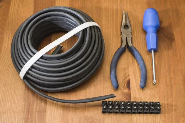 Bir elektrikli tel, boru, tornavida ve pense kahverengi tahta masada