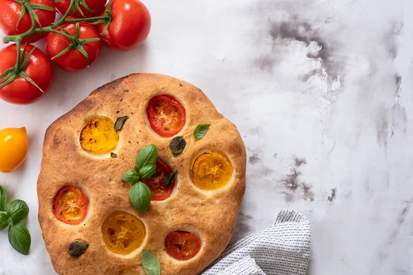 Focaccia with tomatoes and basil. Italian bread. Top view. Copy space.