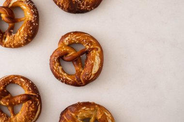 Beyaz zemin üzerine tuz ile taze pişmiş ev yapımı yumuşak pretzel. Üstten görünüm.