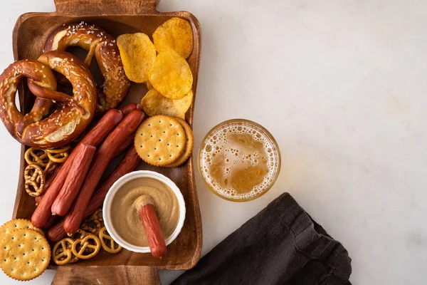 Snack to beer, Bavarian sausages, chips, brezels, crackers and mustard. Oktoberfest food, appetizing beer snacks set for big company.