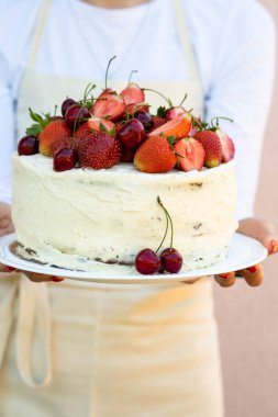 Bir kadın bir kek çilek ile tutuyor. Yaz konsepti.