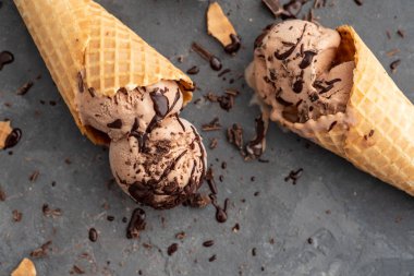 Ev yapımı çikolatalı dondurma waffle külah, dondurma, kakao ve çikolata parçaları için bir kaşıkla. Bir koyu gri masaya. Uzay yakın görünüm Kopyala