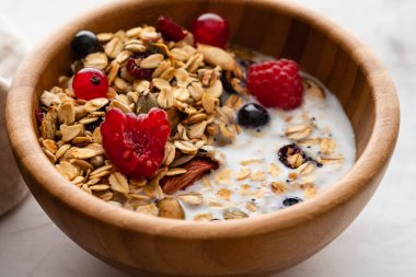 Sağlıklı kahvaltı pişmiş ev yapımı granola, taze meyveler, taze çilek ve süt beyaz bir tablo ile bir kase. Kopya alanı.