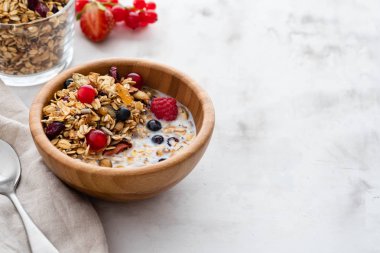 Sağlıklı kahvaltı pişmiş ev yapımı granola, taze meyveler, taze çilek ve süt beyaz bir tablo ile bir kase. Kopya alanı.