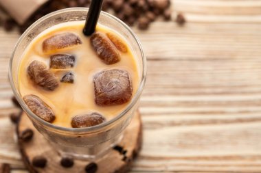 Soğuk kahve cam ahşap masa arka plan üzerinde buz küpleri ile. Buzlu kahve. Kopya alanı.