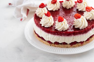 Ahududu cheesecake ile çırpılmış krema ve taze ahududu beyaz tabakta. Kopya alanı.