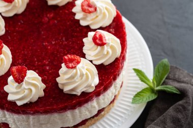 Ahududu cheesecake ile çırpılmış krema ve taze ahududu beyaz tabakta. Kopya alanı.