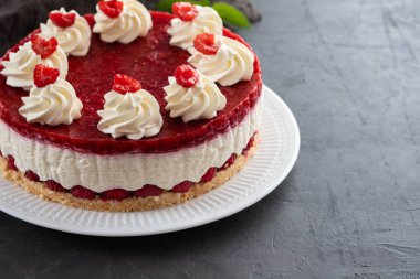 Ahududu cheesecake ile çırpılmış krema ve taze ahududu beyaz tabakta. Kopya alanı.