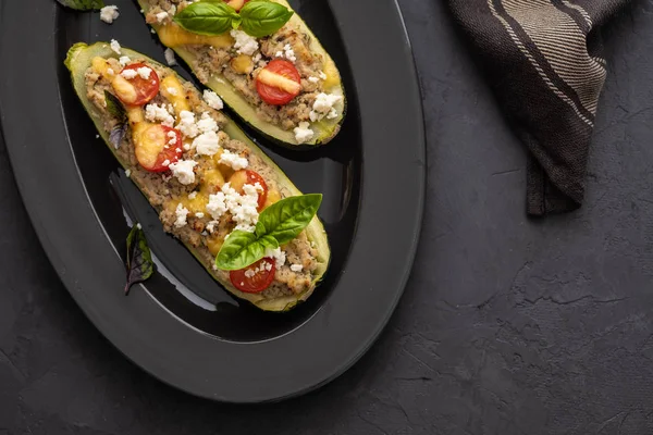 Kıyılmış et ile dolması kabak siyah bir zemin üzerine peynir. Fırında pişmiş. Kopya alanı.