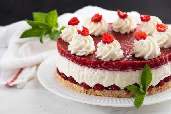 Ahududu cheesecake ile çırpılmış krema ve taze ahududu beyaz tabakta. Kopya alanı.