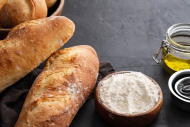 Karanlık bir arka plan üzerinde malzemelerle taze ekmek. Kopya alanı.