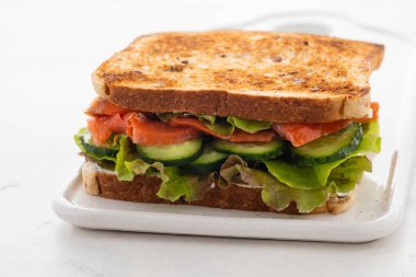 Somon, taze salata ve bir beyaz tahta üzerinde salatalık sandviç. Kopya alanı.