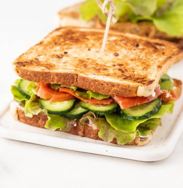 Somon, taze salata ve bir beyaz tahta üzerinde salatalık sandviç. Kopya alanı.