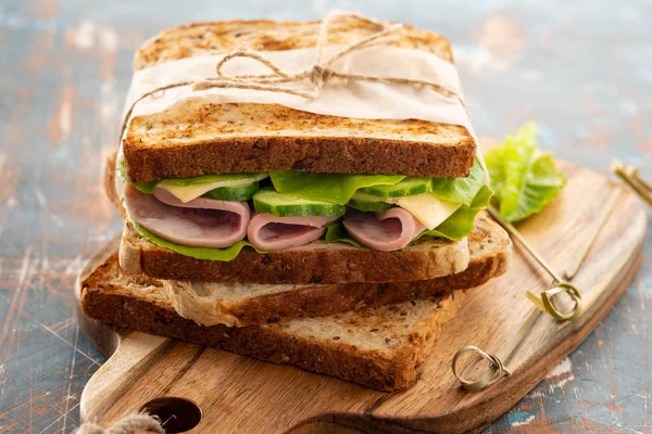 Close-up foto van een club sandwich. Sandwich met meet, ham, salami, salade, groenten, sla op een vers gesneden brood op houten achtergrond. Kopiëren van ruimte. — Stockfoto