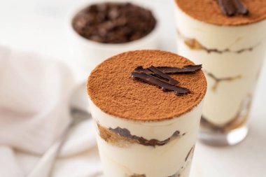 Bir bardak beyaz zemin üzerine kahve çekirdekleri ile tiramisu. Kopya alanı.