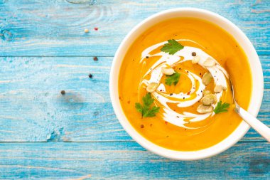 Maydanoz üzerinde mavi arka plan üstten görünüm kabak ve havuç çorbası.