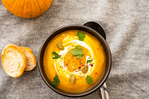 Soupe de citrouille avec des graines de citrouille sur un bol sur fond textile de lin, vue de dessus. Concept d'automne . — Photo