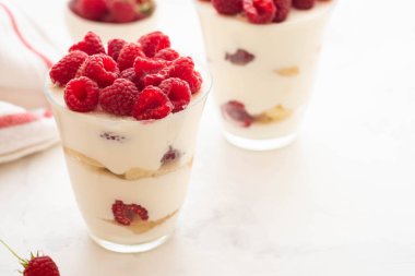 Ahududu tatlı, cheesecake, ahududulu tiramisu, önemsememek, mus bir bardak beyaz bir arka plan üzerinde.