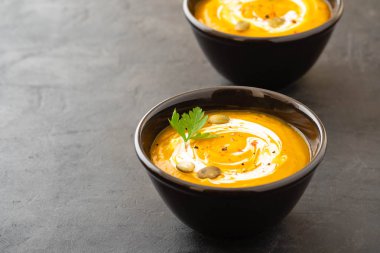 Taze kabak ile bir kase, sarımsak ve maydanoz otlar siyah bir zemin üzerine balkabağı çorbası. Sonbahar konsepti.