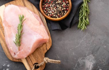 Baharat ve otlar ile siyah kesme tahtası üzerinde çiğ hindi fileto. Pişirme malzemeleri. Doğal sağlıklı gıda kavramı. Metin için yer ile üstten görünüm