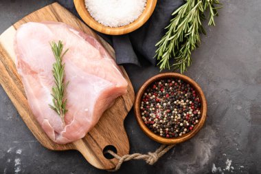 Baharat ve otlar ile siyah kesme tahtası üzerinde çiğ hindi fileto. Pişirme malzemeleri. Doğal sağlıklı gıda kavramı. Metin için yer ile üstten görünüm