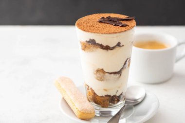 Bir bardak beyaz zemin üzerine kahve çekirdekleri ile tiramisu. Kopya alanı.