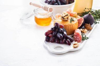 Peynir tabağı üzüm, reçeli, incir, kraker ve beyaz zemin üzerine fındık ile devam eder. Kopya alanı.